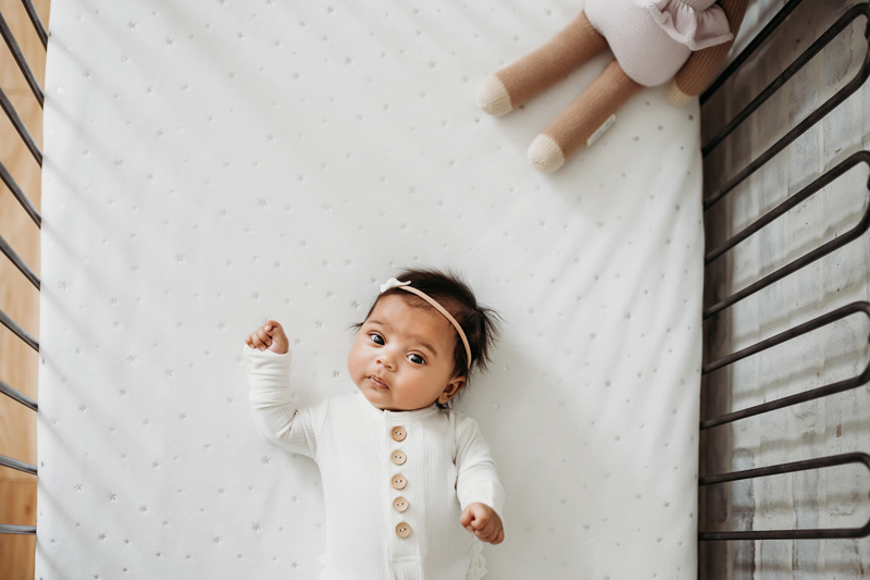 Newborn Photography, a little baby girl lays in her crib wide eyed with wonder