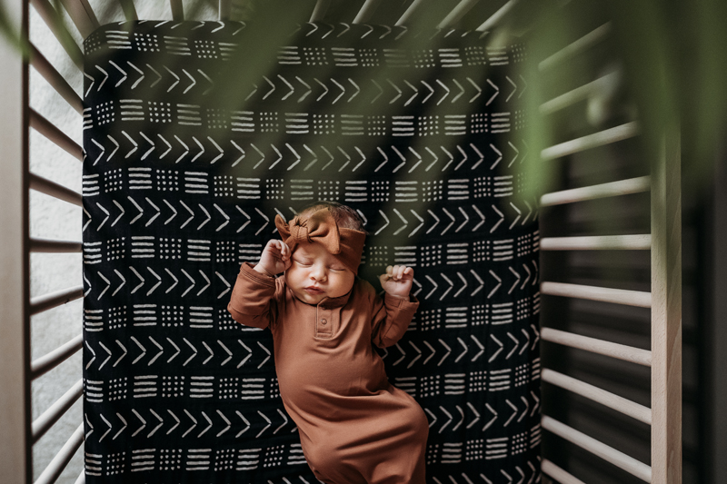 Newborn Photography, baby squirms in a crib as if she were waking up from a cozy nap